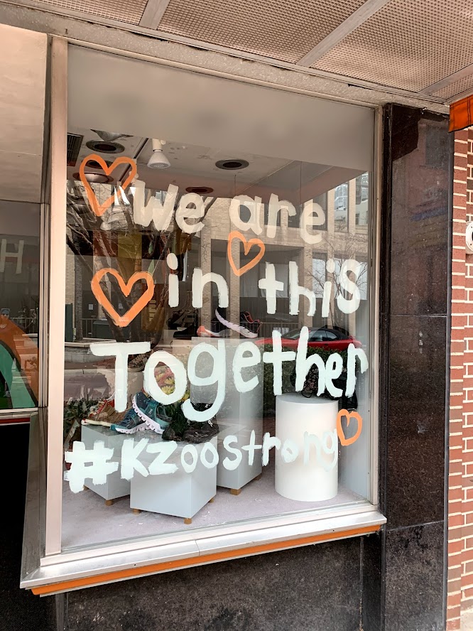 Window display with handwritten message reading 'We are in this together' and '#KZooStrong' surrounded by heart drawings.